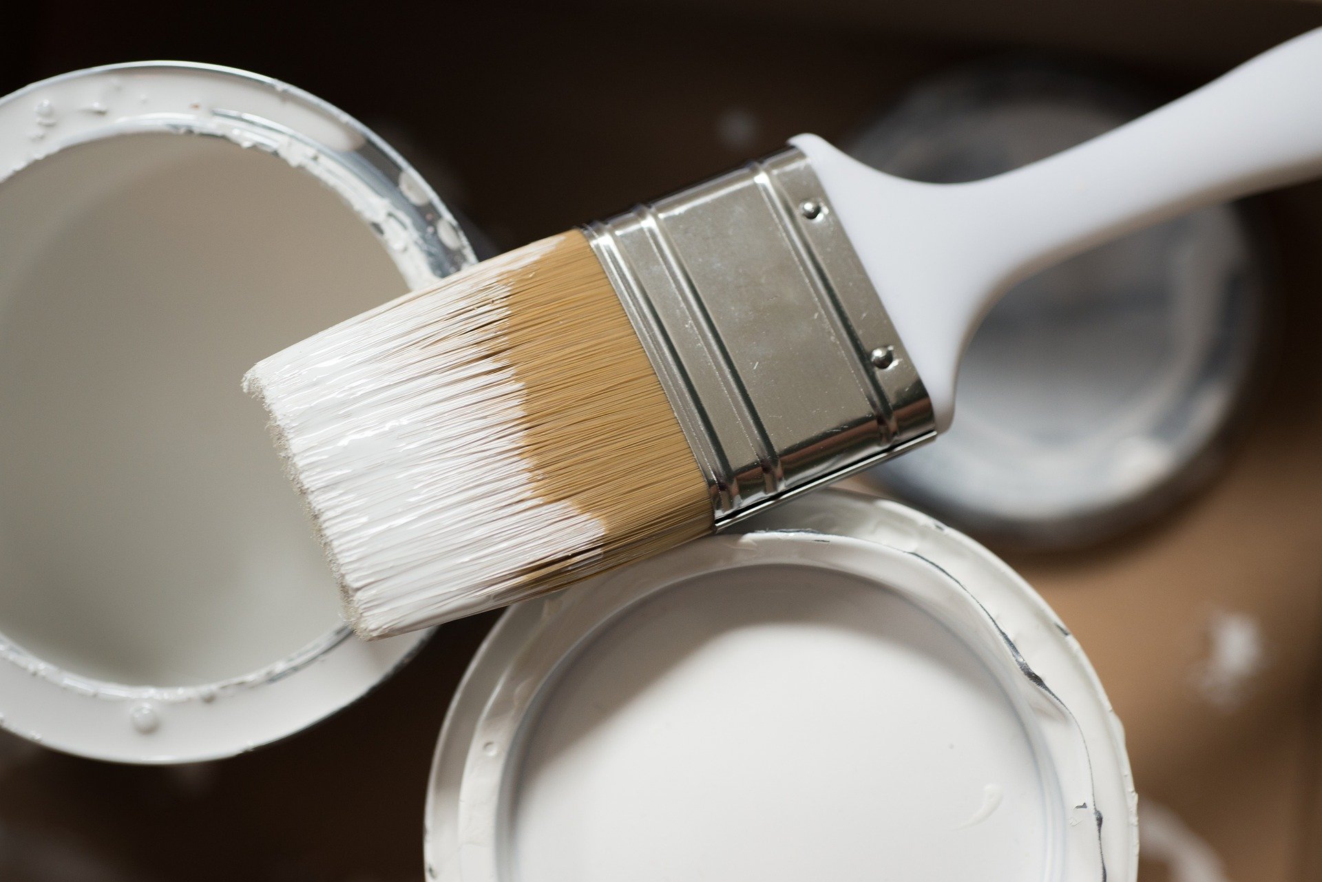 Paint brush resting on tin of white paint